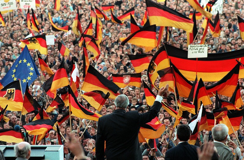 
              FILE - In this Feb. 20, 1990 file photo the West-German Chancellor Helmut Kohl is framed by German flags as he waves to spectators during a campaign rally in Erfurt, then still GDR. Helmut Kohl died June 16, 2017. (Heinz Wieseler/dpa via AP)
            