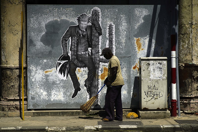 
              A street sweeper cleans the sidewalk under a mural painting depicting U.S. President Donald Trump, in Havana, Cuba, Friday, June 16, 2017. President Trump is en route to Miami, where he'll announce his plans for halting the flow of U.S. cash to Cuba's military and security services while maintaining diplomatic relations, in a partial reversal of the Obama administration policies. (AP Photo/Ramon Espinosa)
            