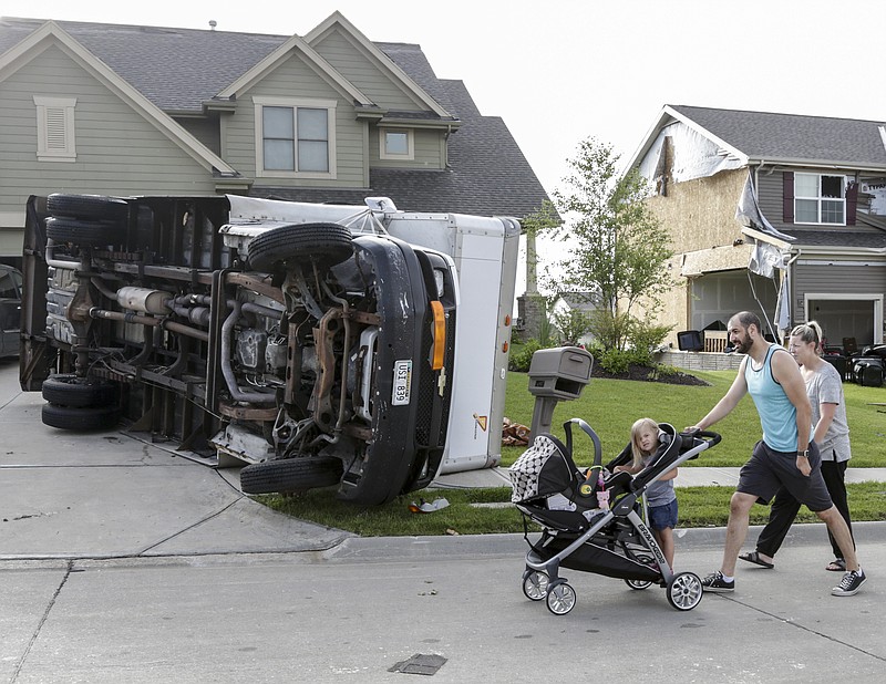 
              Vincent and Lindsey Mercado and their children walk past an overturned truck and weather damaged homes in the Hyda Hills neighborhood in Bellevue, Neb., Saturday, June 17, 2017. A severe weather front passed through the area the previous evening. (AP Photo/Nati Harnik)
            