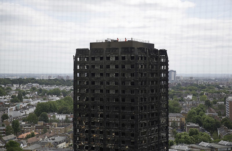 
              Emergency workers walk on the roof of the fire-gutted Grenfell Tower in London, Friday, June 16, 2017, after a fire engulfed the 24-storey building on Wednesday morning. Grief over a high-rise tower blaze that killed dozens of people turned to outrage Friday amid suggestions that materials used in a recent renovation project may have contributed to the disaster. (AP Photo/Matt Dunham)
            