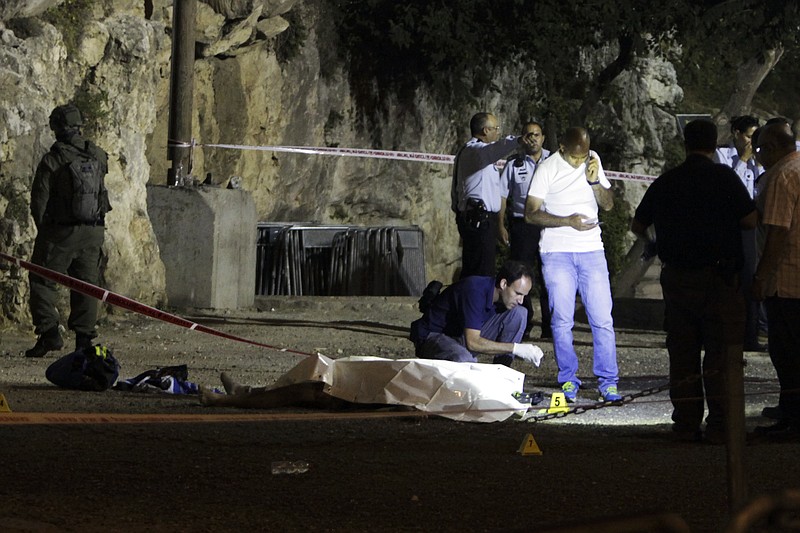 
              ADDS CONDITION OF THE POLICE OFFICER -Israeli police stand around a body of a Palestinian in Jerusalem, Friday, June 16, 2017. Three Palestinians armed with an automatic weapon and knives attacked Israeli officers on duty near Jerusalem's Old City in twin attacks at two locations Friday evening, critically wounding one before they were shot and killed. Police officer critically wounded died of her wounds. (AP Photo/Mahmoud Illean)
            
