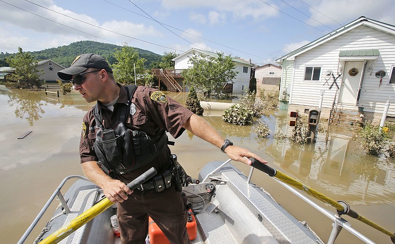 
              FILE - In this Saturday, June 25, 2016 file photo, Lt. Dennis Feazell, of the West Virginia Department of Natural Resources, watches for debris as he and a co-worker search flooded homes in Rainelle, W. Va.  The town of Rainelle, population 1,500, lost five residents and dozens of homes in the June 23, 2016 floods. The Christian ministry Appalachia Service Project is building at least 50 homes and fixing others, while another group is removing sediment from Rainelle’s flood-control channels.   (AP Photo/Steve Helber, File)
            