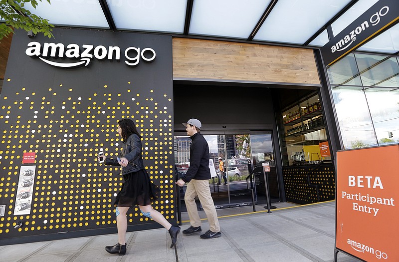 
              FILE - In this Thursday, April 27, 2017, file photo, people walk past an Amazon Go store, currently open only to Amazon employees, in Seattle. Amazon Go shops are convenience stores that don't use cashiers or checkout lines, but use a tracking system that of sensors, algorithms, and cameras to determine what a customer has bought. Amazon says the company has no plans to use such sensors to automate the cashier jobs at Whole Foods, which Amazon is acquiring. Still, it’s the kind of technology that could help cut costs down the road, and that others may look to as well. (AP Photo/Elaine Thompson, File)
            