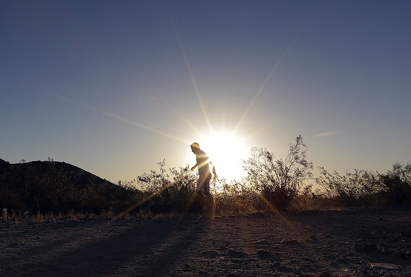 
              FILE - In this June 16, 2017, file photo, a man runs through section of South Mountain Park at sunrise to avoid the excessive heat in Phoenix. A record heat wave is rolling into Arizona, Nevada and California, threatening to bring 120-degree temperatures to Phoenix by early next week. The southwestern U.S. is about to feel the wrath of a punishing heat wave that includes a forecast of 120 degrees in Phoenix _ a temperature not seen in the desert city in more than 20 years. (AP Photo/Matt York, File)
            