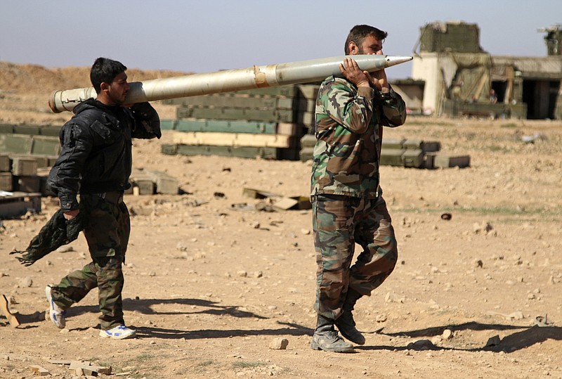 
              FILE - In this file photo taken on Wednesday, Feb. 17, 2016, soldiers from the Syrian army carry a rocket to fire at Islamic State group positions in the province of Raqqa, Syria. Syrian government and allied troops have inserted themselves into the battle against Islamic State militants by capturing key areas on the flanks of the coalition-led battle to seize Raqqa. They have positioned themselves as indispensable possibly spoilers in the fight to uproot the militants from Syria. (Alexander Kots/Komsomolskaya Pravda via AP, File)
            