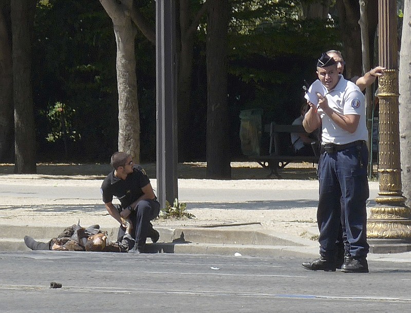 
              In this photo provided by Noemie Pfister, a French gendarme kneels near the dead body of a man who rammed into a police convoy and detonated an explosive device on the Champs Elysees avenue in Paris, France, Monday, June 19, 2017. Two French police officials say the man who rammed into a police convoy on Paris' Champs-Elysees was a 31-year-old man from a Paris suburb who had been flagged for extremism. (Noemie Pfister via AP)
            