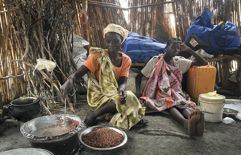 
              In this photo taken Monday, June 19, 2017, Elizabeth Adwok, left, an ethnic Shilluk who arrived with her seven children in April after having been forcefully displaced from her home three times since South Sudan's conflict began, cooks sorghum in her small hut in the village of Aburoc, South Sudan where she lives with other displaced people. A new report by Amnesty International says South Sudanese forces burned, shelled and ransacked homes between January and May, killing civilians and forcing thousands from the Shilluk ethnic minority to flee. (AP Photo/Sam Mednick)
            