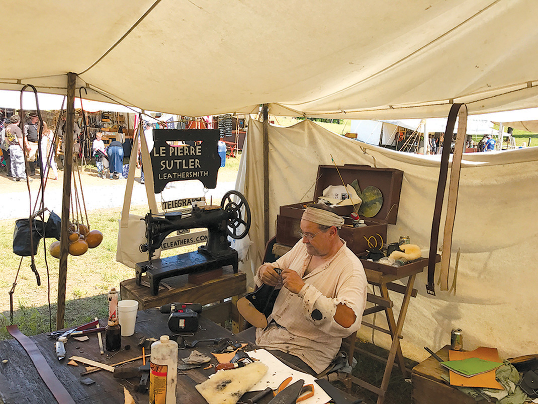 Leathersmith Fred Healy sews a holster in his booth on sutler's row.