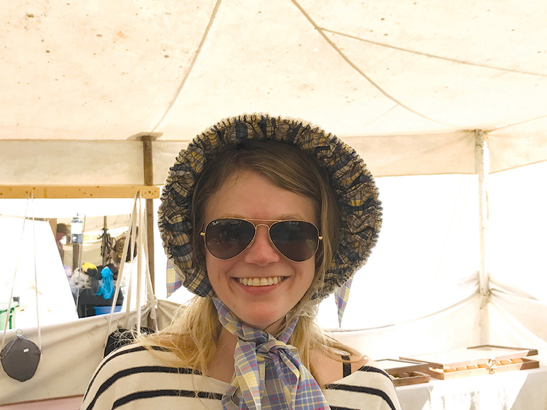 Emily Crisman tries out a period bonnet on sutler's row.
