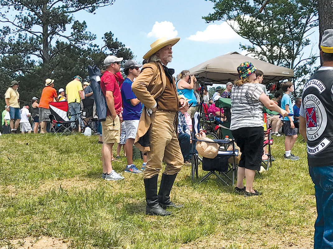 A woman in period dress mixes with spectators in modern-day attire.