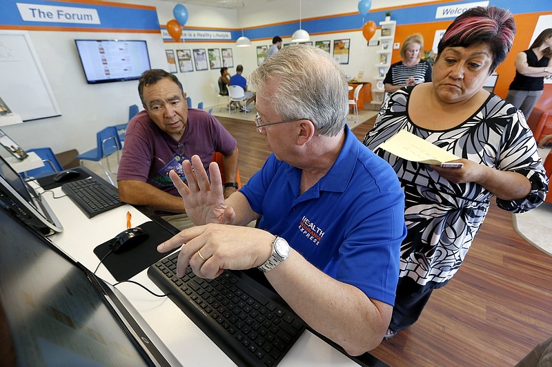 
              FILE - In this Tuesday, Oct. 1, 2013, file photo, Alan Leafman, center, president of Health Insurance Express, Inc., helps Raquel Bernal, right, and her husband John Bernal, both of Apache Junction, Ariz., navigate the nation's health care insurance system online at the Health Insurance Express store in Mesa, Ariz. Enough insurers are planning to sell coverage through the Affordable Care Act in 2018 to keep the market place working, if only barely, in most parts of the country. However competition in many markets has dwindled to one insurer, or none in some cases, and another round of steep price hikes is expected to squeeze consumers who don’t receive big income-based tax credits to help pay their bill. (AP Photo/Ross D. Franklin, File)
            