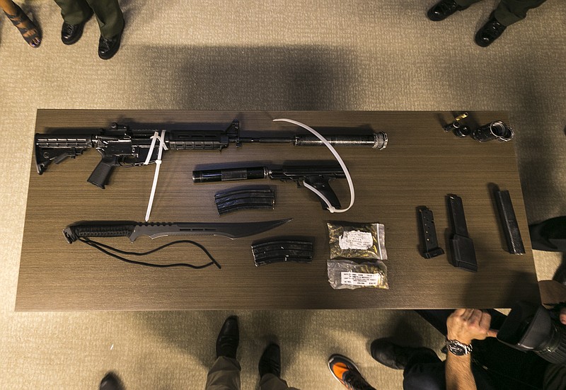 
              Los Angeles Sheriff department transit deputies show a cache of illegal arms found on a suspect's duffle bag after arresting him for urinating in public, during a news conference in Los Angeles, Wednesday, June 21, 2017. The Sheriff's Department said that on him they found a loaded handgun that is restricted for law enforcement use, another loaded, high-powered firearm that resembles a rifle, two loaded, high-capacity magazines, a silencer, and a large survival knife that was nearly as long as a sword. (AP Photo/Damian Dovarganes)
            