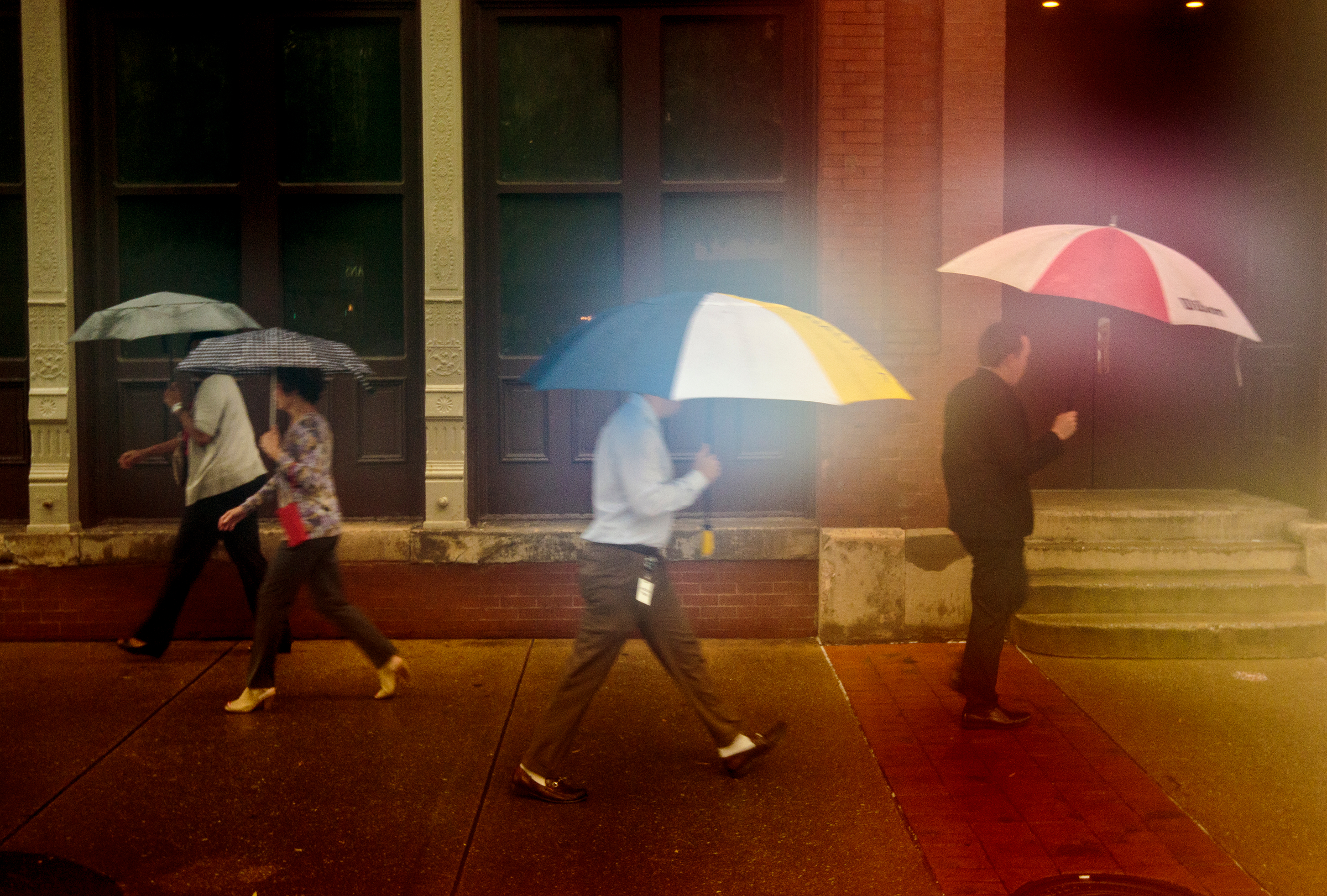 Pedestrians walk on Broad Street after tropical storm Cindy brought rainfall to the region on Thursday, June 22, 2017, in Chattanooga, Tenn. The shift in colors and glow in this photograph are the result of condensation forming on the lens of the photographer's camera.