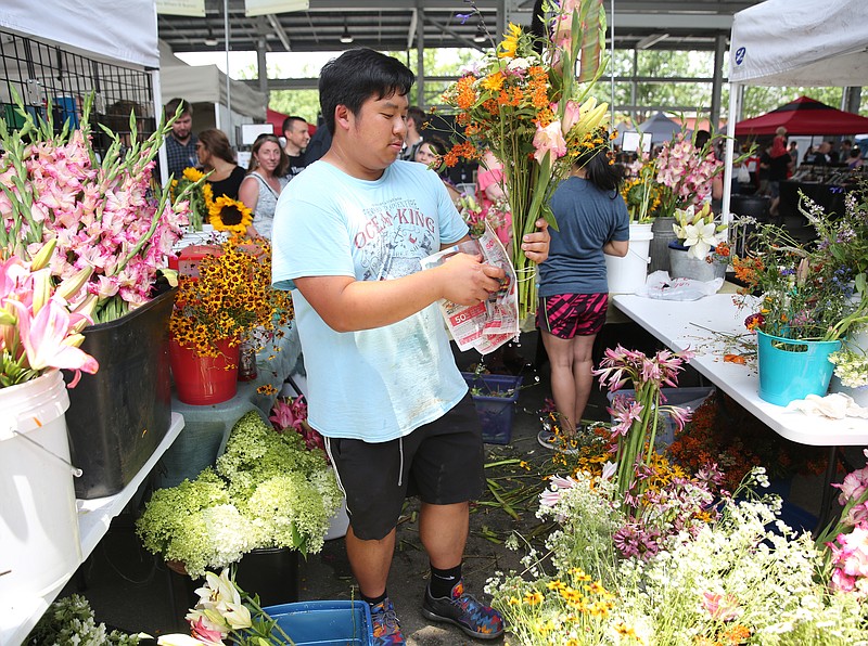 Erick Yang of Pa and Flowers creates customized arrangements for customers during the Father's Day Bacon, Blues and Brews event at the Chattanooga Market at the First Tennessee Pavilion in Chattanooga, Tenn., Sunday, June 18, 2017. Pa and Flowers, which is out of Carrollton, Ga., sells customized arrangements for $20 and traditional preprepared bouquets for $10 at the market. 