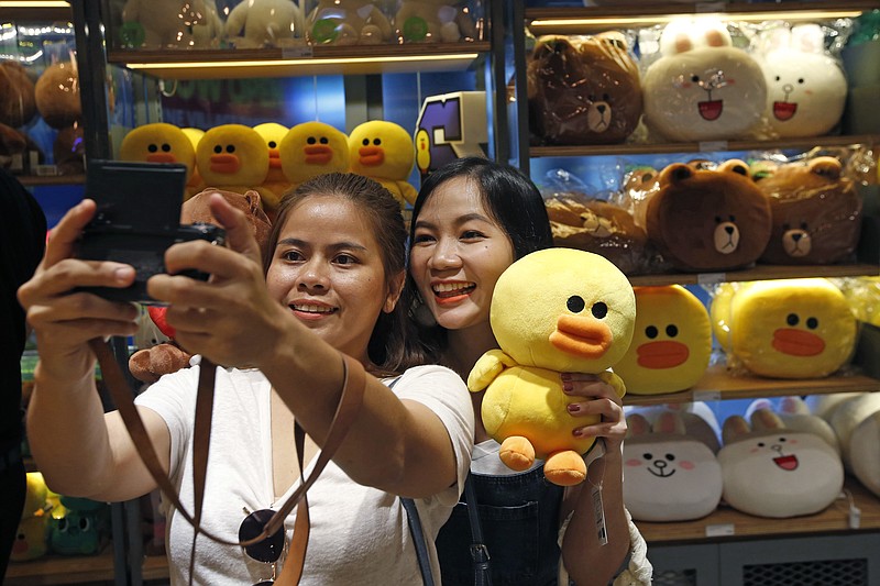 
              Customers take a selfie with merchandise at Line Village in Bangkok, Thailand, Thursday, June 22, 2017. Thailand's most popular text-messaging service will open its doors to the public Friday with an extravagant digital theme park called Line Village Bangkok. (AP Photo/Sakchai Lalit)
            
