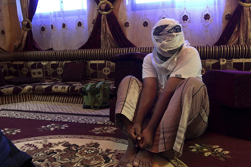 A former detainee shows how he was kept in handcuffs and leg shackles while held in a secret prison at Riyan airport in the Yemeni city of Mukalla in this May 11, 2017 photo. He covered his face for fear of being detained again. He and other former detainees say abuses are widespread in a network of secret prisons run by the United Arab Emirates and its Yemeni allies, into which hundreds detained in the hunt for al-Qaida militants have disappeared. (AP Photo/Maad El Zikry)