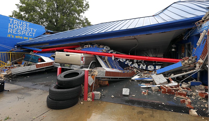 Several cars sit under the collapsed roof of an Express Oil Change after a possible tornado touched down destroying several businesses, Thursday, June 22, 2017, in Fairfield, Ala. (AP Photo/Butch Dill)
