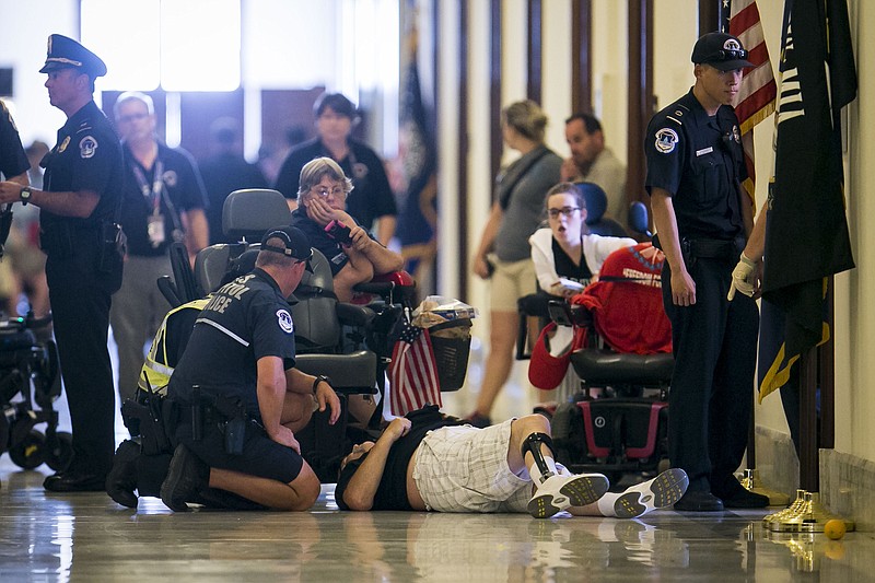 Protesters staging a "die-in" are removed from outside the office of Senate Majority Leader Mitch McConnell (R-Ky.) on Capitol Hill in Washington, Thursday after McConnell unveiled a bill that would make deep cuts to Medicaid and end the mandate that most Americans have health insurance. (Al Drago/The New York Times)