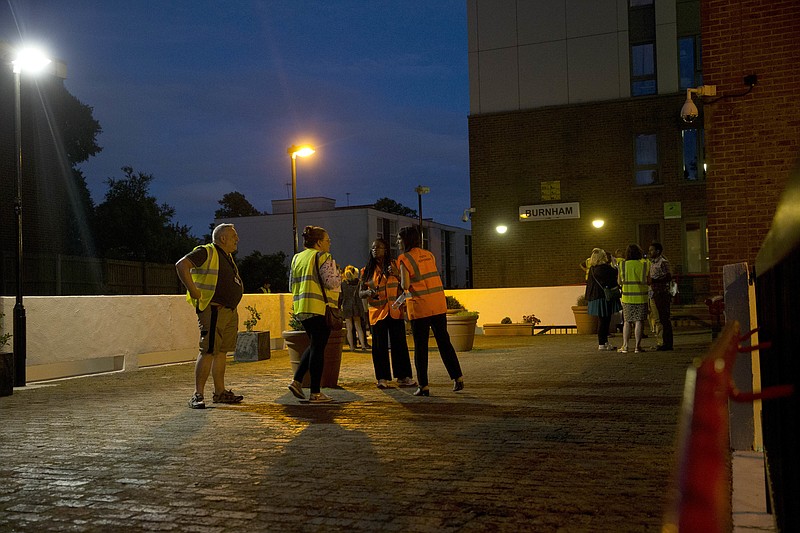 
              Camden council representatives talk as they help residents as they are evacuated from the Burnham residential tower block on the Chalcots Estate, in the borough of Camden, north London, Friday, June 23, 2017. A local London council has decided to evacuate some 800 households in apartment buildings it owns because of safety concerns following the devastating fire that killed 79 people in a west London high-rise. (AP Photo/Alastair Grant)
            