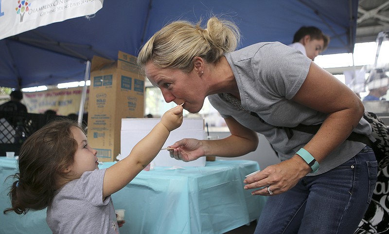 Two-year-old Bradlie Perry, left, gives her mom Christine Perry a bite of ice cream during the Ice Cream Social at the Chattanooga Market at the First Tennessee Pavilion on Sunday, June 25, in Chattanooga, Tenn. The Ice Cream Social raised money for the Chambliss Center for Children. Tickets were purchased for six dollars and included two ice cream flavors to try from five creameries: Clumpies Ice Cream Co., Cold Stone Creamery, The Ice Cream Show, Mayfield and Milk and Honey. After trying all ten flavors available, participates could vote on their favorite flavor.