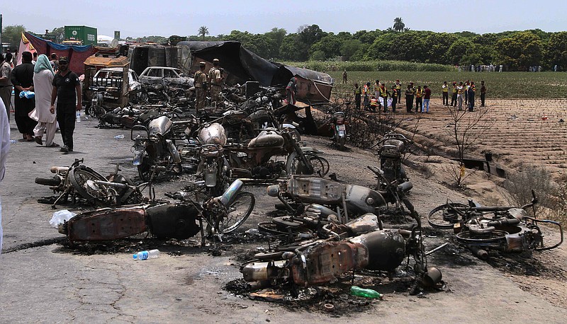 Pakistan army soldiers stands guard while rescue workers examine the site of an oil tanker explosion at a highway near Bahawalpur, Pakistan, Sunday, June 25, 2017. An overturned oil tanker burst into flames in Pakistan on Sunday, killing more than one hundred people who had rushed to the scene of the highway accident to gather leaking fuel, an official said. (AP Photo/Iram Asim)