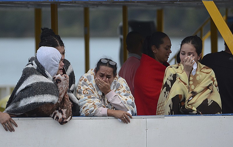 
              People who survived a sunken ferry, cry as they wait for more information about their missing friends and relatives, at a reservoir in Guatape, Colombia, Sunday, June 25, 2017. Nine people were dead and 28 missing after a tourist ferry packed with around 170 passengers for the holiday weekend capsized Sunday on a reservoir near the Colombian city of Medellin, officials said. (AP Photo/Luis Benavides)
            