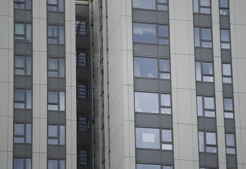 
              A young person looks out from inside the Dorney block, part of the Chalcots Estate in the borough of Camden, north London, Saturday June 24, 2017, after the local council evacuated some 650 homes overnight. The apartments were evacuated overnight after fire inspectors concluded that the buildings, in north London's Camden area, were unsafe because of problematic fire doors, gas pipe insulation, and external cladding similar to that blamed for the rapid spread of a fire that engulfed Grenfell Tower on June 14. (AP Photo/Alastair Grant)
            