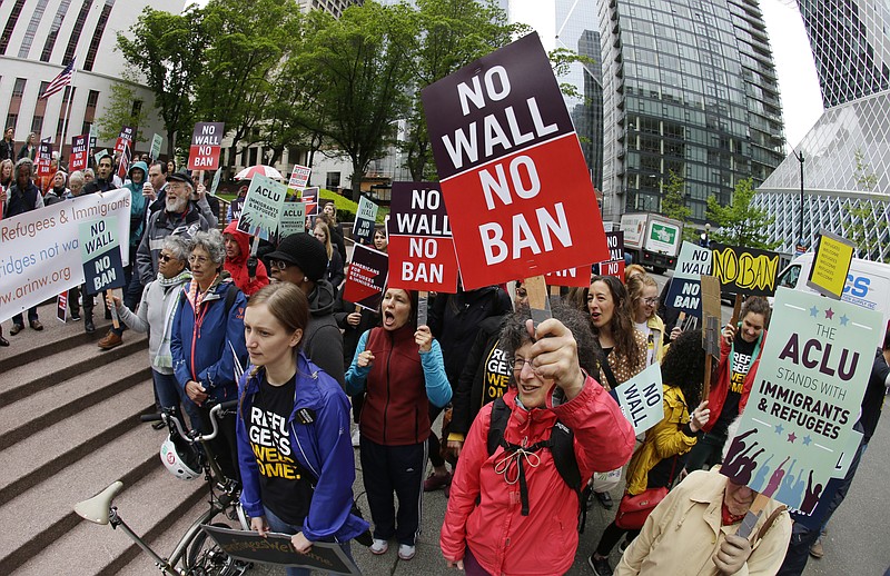 
              FILE - In this May 15, 2017 file photo, protesters wave signs and chant during a demonstration against President Donald Trump's revised travel ban, outside a federal courthouse in Seattle. The Supreme Court is letting the Trump administration enforce its 90-day ban on travelers from six mostly Muslim countries, overturning lower court orders that blocked it. The action Monday, June 26, 2017, is a victory for President Donald Trump in the biggest legal controversy of his young presidency. (AP Photo/Ted S. Warren, File)
            