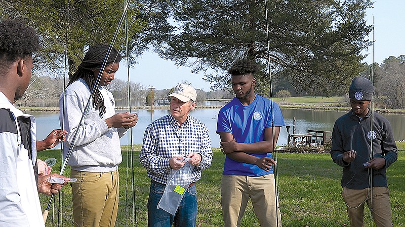 Juwan Hill, left, and Umar Muhammad, right, ask Perk Perkins a question during their fly fishing lesson. Perkins explained how fly fishing works and taught the students how to cast for nearly two hours before going out on the water.