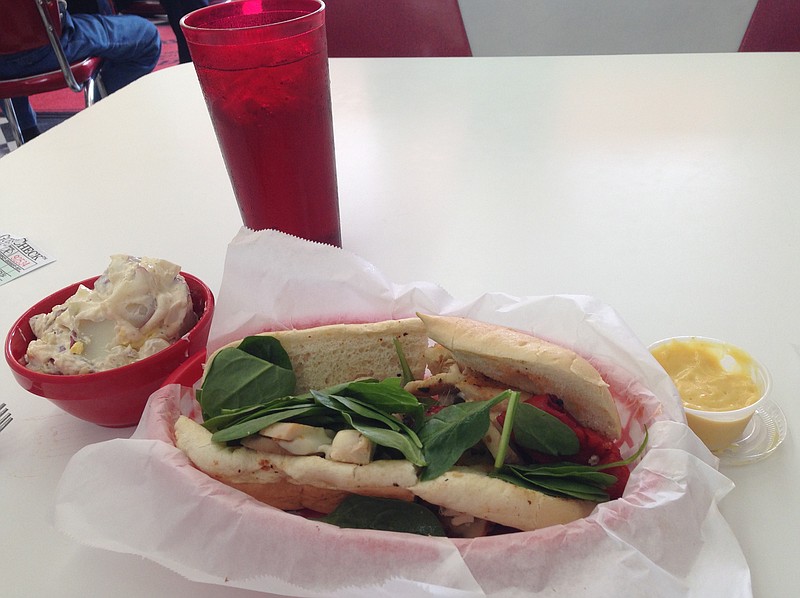 A grilled chicken melt, shown, made with grilled chicken, roasted red peppers, mushrooms and baby spinach topped with melted Parmesan and provolone cheeses comes on a grilled hoagie roll with a side of house potato salad.