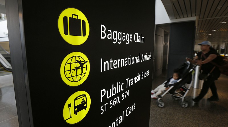 
              A woman pushes a stroller near a sign for international arrivals at the Seattle-Tacoma International Airport, Monday, June 26, 2017, in Seattle. The U.S. Supreme Court said Monday that President Donald Trump's travel ban on visitors from Iran, Libya, Somalia, Sudan, Syria and Yemen can be enforced if those visitors lack a "credible claim of a bona fide relationship with a person or entity in the United States," and that justices will hear full arguments in October 2017. (AP Photo/Ted S. Warren)
            