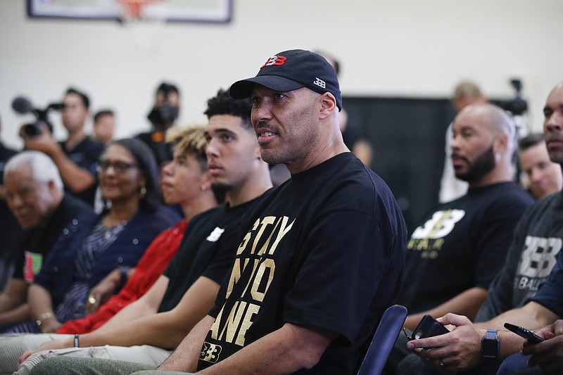 
              FILE - In this June 23, 2017, file photo, LaVar Ball, center, father of Los Angeles Lakers draft pick Lonzo Ball, listens to his son during the NBA basketball team's news conference in El Segundo, Calif. LaVar and Lonzo appeared on "WWE Raw" June 26, 2017.  (AP Photo/Jae C. Hong, File)
            