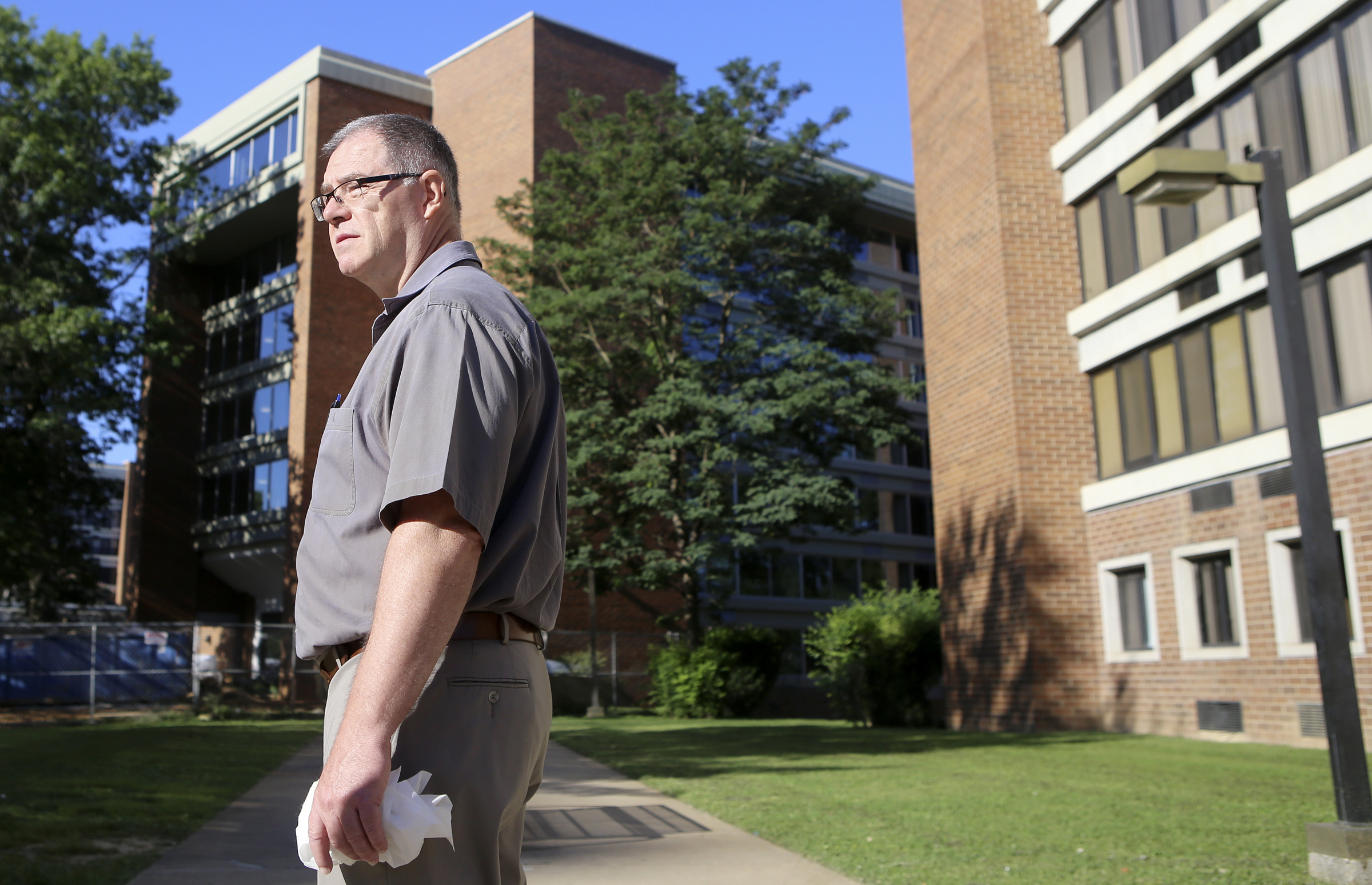 Lonnie Edwards, the project manager for the renovation of Boynton Terrace Apartments, stands outside of a non-renovated building, right, and a renovated building, back, after leading a tour on Wednesday, June 28, in Chattanooga, Tenn.