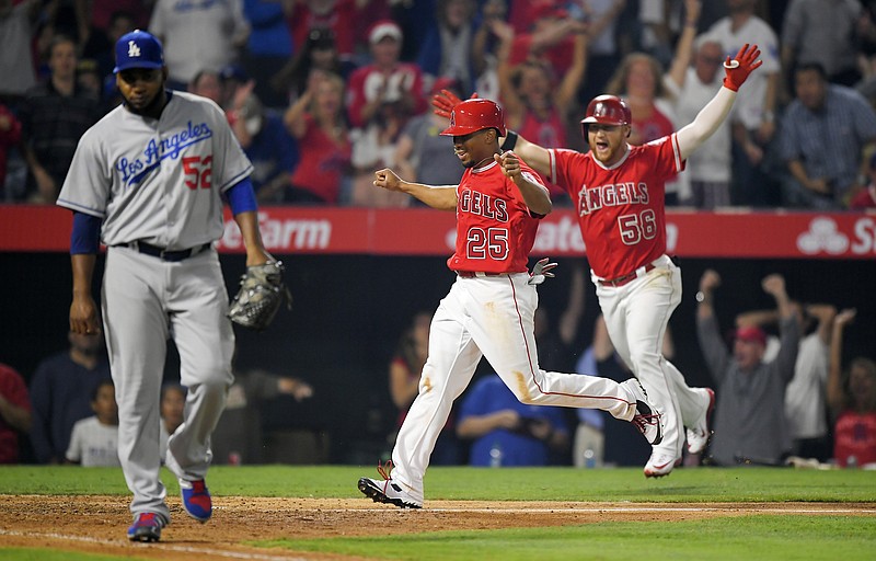 
              Los Angeles Angels' Ben Revere, center, celebrates along with Kole Calhoun, right, as he scores the game-winning run on a throwing error by Los Angeles Dodgers catcher Yasmani Grandal on an at-bat by Cameron Maybin, as relief pitcher Pedro Baez, left, walks off during the ninth inning of a baseball game, Wednesday, June 28, 2017, in Anaheim, Calif. The Angels won 3-2. (AP Photo/Mark J. Terrill)
            