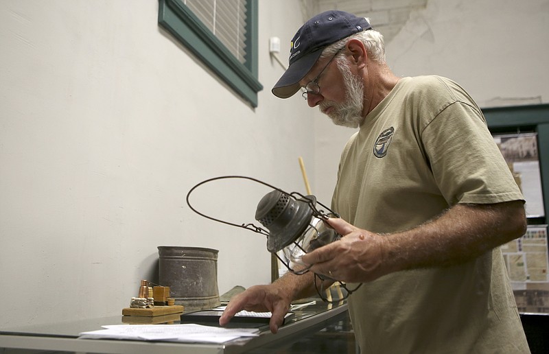 Steve Smith holds a railroad lantern as he works on setting up artifacts at the Good Old Days Museum in the old Soddy Bank building on Thursday, June 29, in Soddy-Daisy, Tenn.