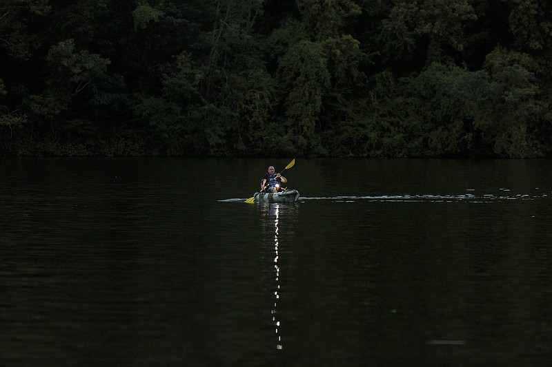 TWRA Officer Barry Baird demonstrates the correct use of a bright white light from a kayak while paddling near the Woltever Creek boat ramp at dusk on Harrison Bay on Friday, June 30, 2017, in Harrison, Tenn. The law requires paddlers to keep a source of bright white light (not red or green) and a life jacket on their vessels for safety.
