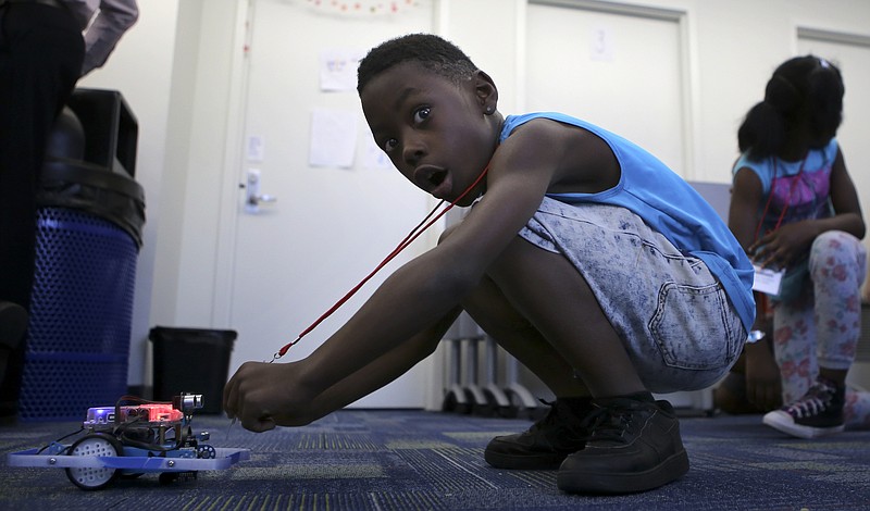 Stephen Smith, 9, reacts as a robot reacts to his name tag being placed in front of its sensors during Tech Town camp at the Edeny Building on Thursday, June 29, in Chattanooga, Tenn.