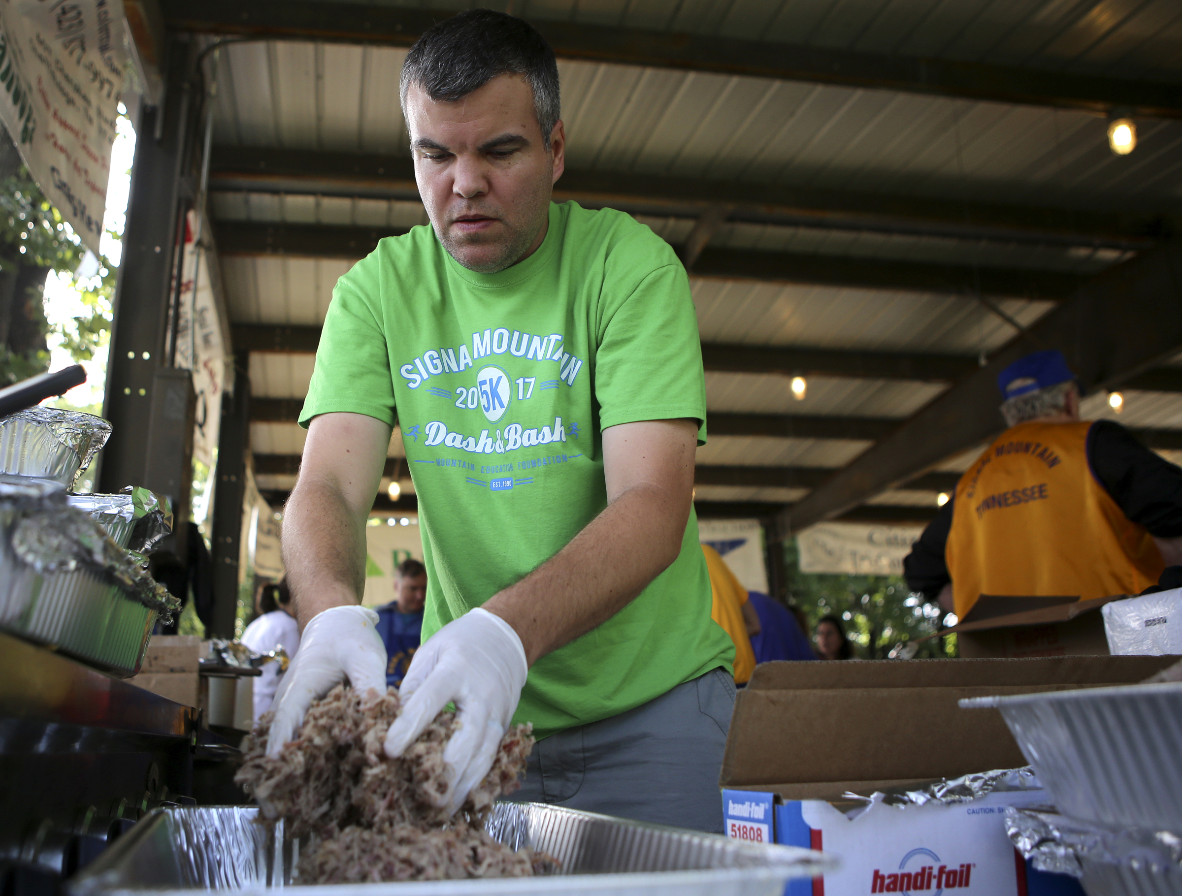 Kurt Stafford piles pulled pork into a tray during the Signal Mountain Lions Club's annual Fourth of July barbecue at Althaus Park on Tuesday, July 4, in Signal Mountain, Tenn. According to club president Gary Lowder, 1,000 pounds of pork was cooked in preparation to serve about 700 patrons.
