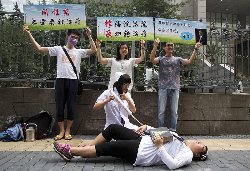 
              FILE - In this July 31, 2014 file photo, gay rights campaigners act out electric shock treatment to protest outside a court when the first court case in China involving so-called conversion therapy is held in Beijing, China. A gay man in central China has successfully sued a mental hospital over forced conversion therapy on June 26, 2017, in what activists are hailing as the first such victory in the country where the LGBT rights movement is gradually emerging form the fringes. (AP Photo/Ng Han Guan, File)
            