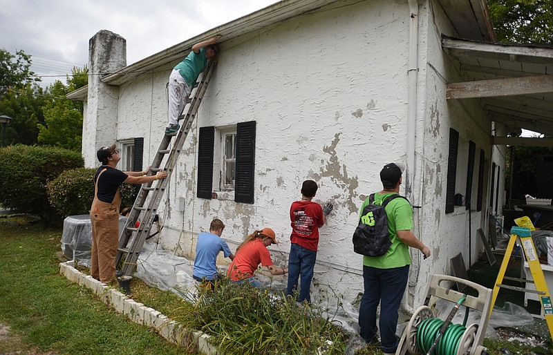 A World Changers group scrapes paint from a home on Alton Park Blvd in this file photo.