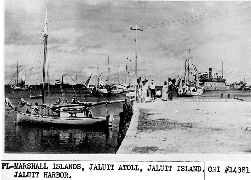 This undated photo discovered in the U.S. National Archives by Les Kinney shows people on a dock in Jaluit Atoll, Marshall Islands. A new documentary film proposes that this image shows aviator Amelia Earhart, seated third from right, gazing at what may be her crippled aircraft loaded on a barge. The documentary "Amelia Earhart: The Lost Evidence," which airs Sunday, July 9, 2017, on the History channel, argues that Earhart and her navigator, Fred Noonan, crash-landed in the Japanese-held Marshall Islands, were picked up by Japanese military and that Earhart was taken prisoner. (Office of Naval Intelligence/U.S. National Archives via AP)