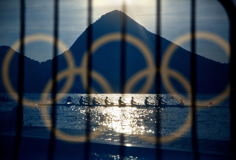 
              FILE - In this Aug. 7, 2016, file photo, rowers are seen through a screen decorated with the Olympic rings as they practice at the rowing venue in Lagoa at the 2016 Summer Olympics in Rio de Janeiro, Brazil. The Olympic Channel, a new Olympic-themed television network makes its debut on Saturday, July 15. (AP Photo/David Goldman, File)
            