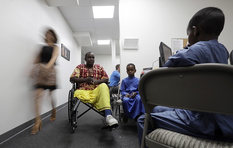 In this July 6, 2017, file photo, Ali Said, of Somalia, center, waits at a center for refugees with his two sons in San Diego. Said, whose leg was blown off by a grenade, says he feels unbelievably lucky to be among one of the last refugees allowed into the United States before stricter rules were to kick in as part of the Trump administration's proposed travel ban. A federal judge in Hawaii further weakened the already-diluted travel ban Thursday, July 13, 2017, by vastly expanding the list of U.S. family relationships that visitors from six Muslim-majority countries can use to get into the country. (AP Photo/Gregory Bull, File)