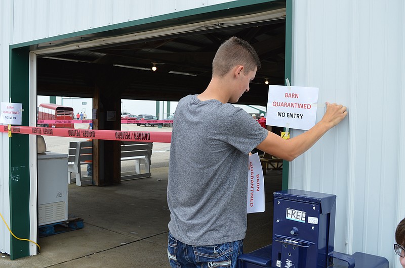 
              In this Thursday, July 13, 2017 photo, Clinton County Junior Fair Board member Ridge Beam places quarantine signs on the hog barn at the Clinton County Fairgrounds in Wilmington, Ohio. State officials have ordered the slaughter of nearly 300 hogs at athe county fair in southwest Ohio after at least two animals tested positive for swine flu.  (Gary Huffenberger/Wilmington News Journal via AP)
            