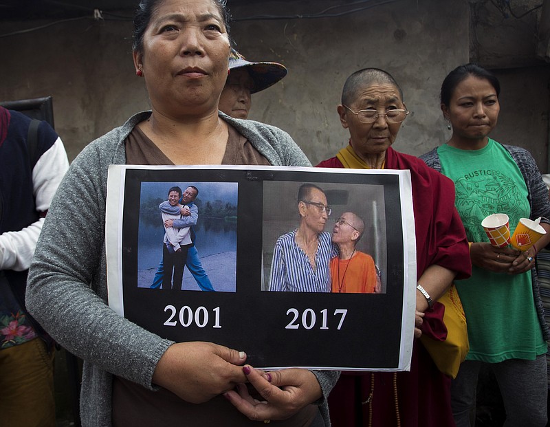 
              An exile Tibetan carries a placard featuring photos of late Nobel Peace Prize laureate Xiaobo Liu, China's most famous political prisoner, during a candlelit vigil to mourn Liu's death, in Dharmsala, India, Friday, July 14, 2017. Liu died Thursday of liver cancer at 61. (AP Photo/Ashwini Bhatia)
            