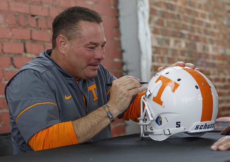 Tennessee football coach Butch Jones autographs a helmet for a fan at the Big Orange Caravan's stop at the First Tennessee Pavilion on Saturday, June 3, 2017, in Chattanooga, Tenn. The event gave fans the chance to meet Tennessee Athletics coaches and new athletic director John Currie.