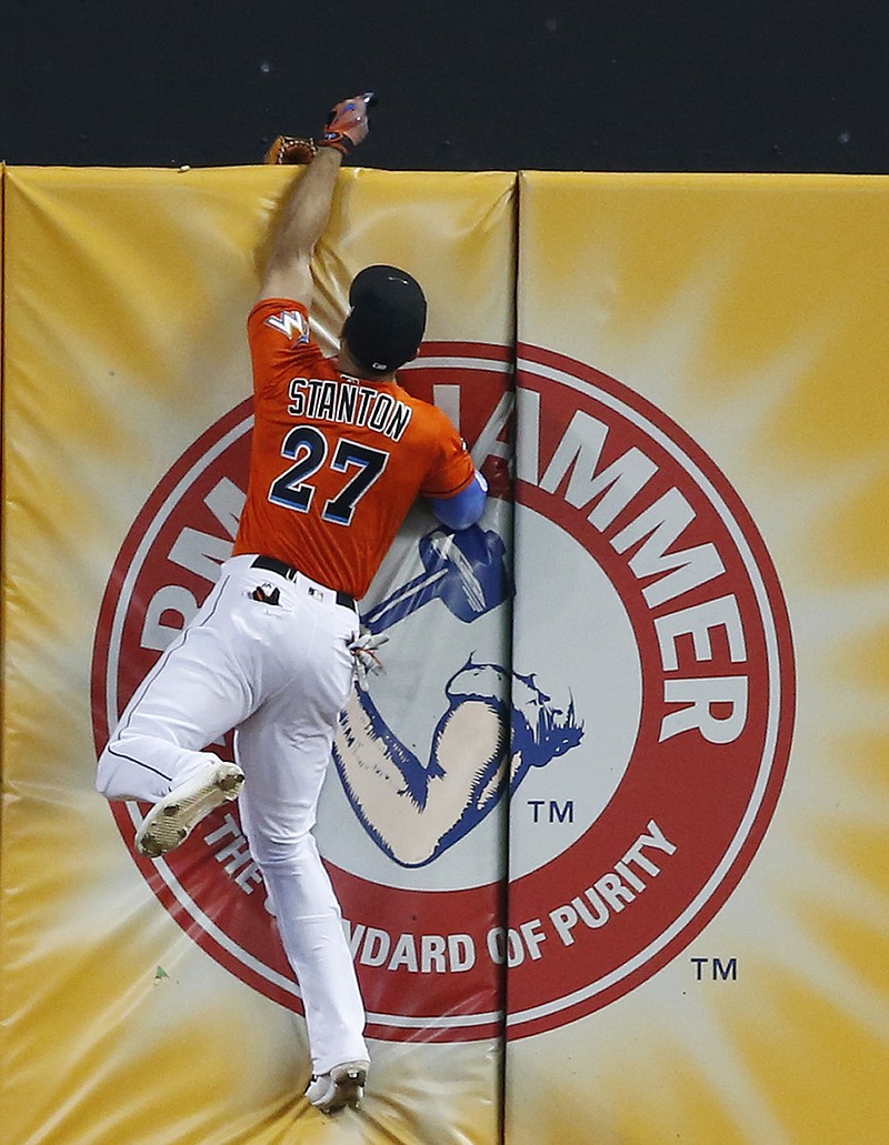 
              Miami Marlins right fielder Giancarlo Stanton loses his glove over the wall as he attempted to catch a triple hit by Los Angeles Dodgers' Chris Taylor during the fourth inning of a baseball game, Sunday, July 16, 2017, in Miami. The Dodgers defeated the Marlins 3-2. When Stanton made a running leap and stretched his left arm above the wall, his glove came off and fell to the other side. (AP Photo/Wilfredo Lee)
            