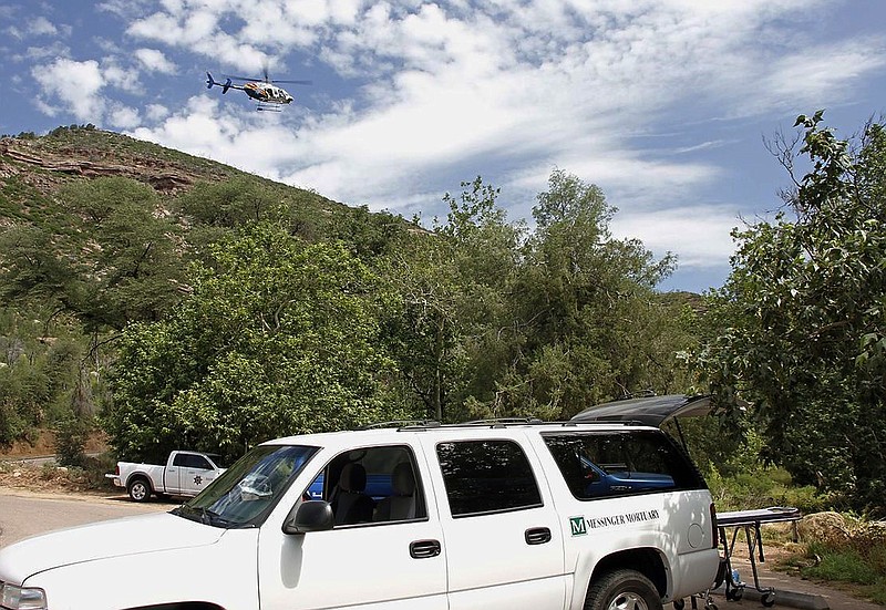 
              A Department of Public Safety helicopter hovers over as a mortuary vehicle awaits for victims on the parking lot of Water Well Campground in the Tonto National Forest, Ariz, Sunday morning, July 16, 2017, following Saturday's deadly flash-flooding at Cold Springs canyon. The flooding came after a severe thunderstorm pounded down on a nearby remote area that had been burned by a recent wildfire, Water Wheel Fire and Medical District Fire Chief Ron Sattelmaier said. (Alexis Bechman/Payson Roundup via AP)
            