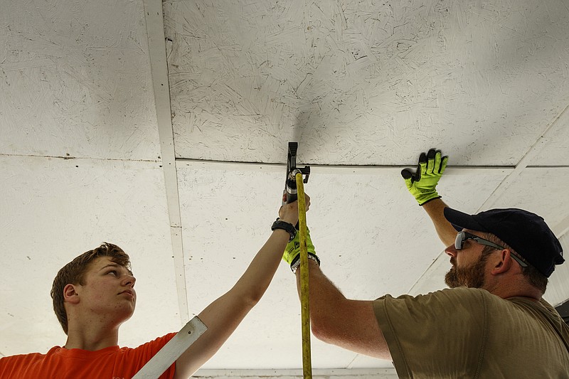 World Changers volunteers Matthew Perry, left, and Chris Rivest repair the porch ceiling of a home on Oak Street last week.