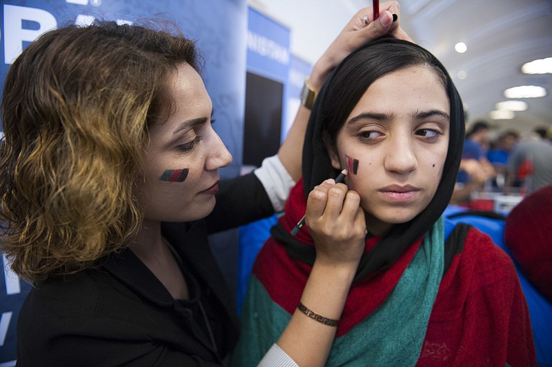 
              Afghanistan team member Somaya Faryuqi, right, has the flag of Afghanistan drawn on her cheek prior to the opening ceremony for the FIRST Global Challenge 2017, in Washington, Sunday, July 16, 2017. They will be competing against entrants from more than 150 countries in the FIRST Global Challenge. It’s the first annual robotics competition designed to encourage youths to pursue careers in math and science. 
(AP Photo/Cliff Owen)
            